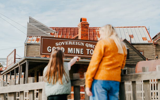 Tourists exploring the Sovereign Hill Gold Mine Tour sign in Ballarat, Australia.