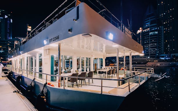Alexandra Sea Lounge Dhow Cruise interior with dining setup at night, Dubai Marina.