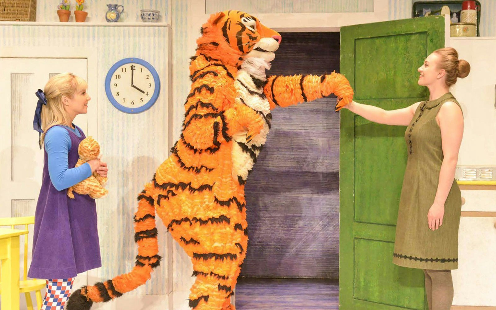 Tiger character greeting woman and child in "The Tiger Who Came to Tea" stage scene.