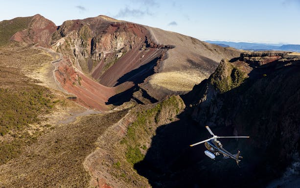Helicopter flying over Mount Tarawera's volcanic landscape during a guided tour in New Zealand.