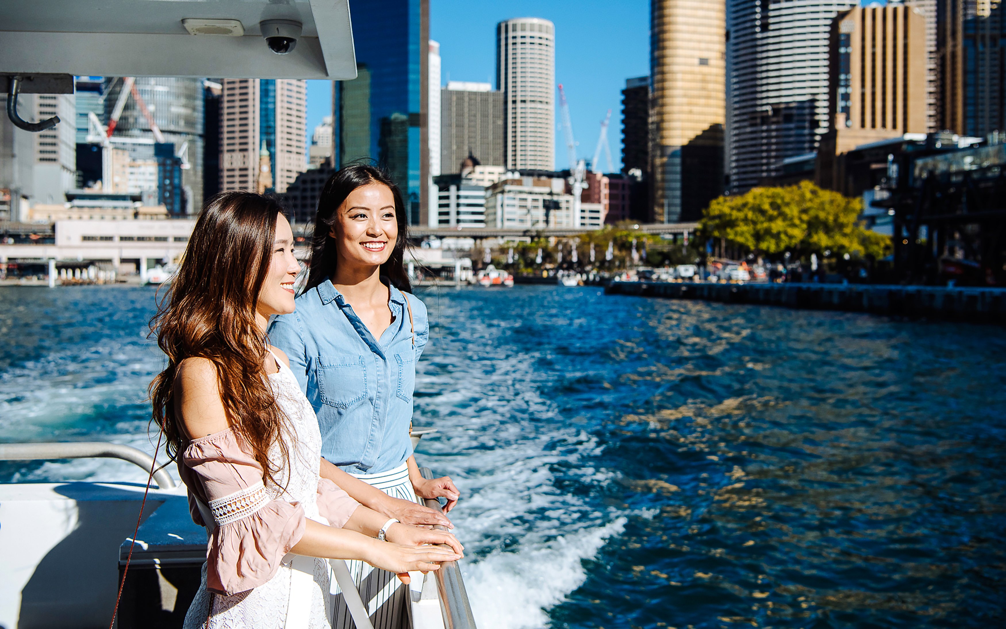 Two people enjoying a Sydney Harbour cruise with city skyline in the background.