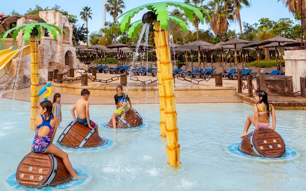 Children playing on water barrels at Aqualand Costa Adeje pool park.