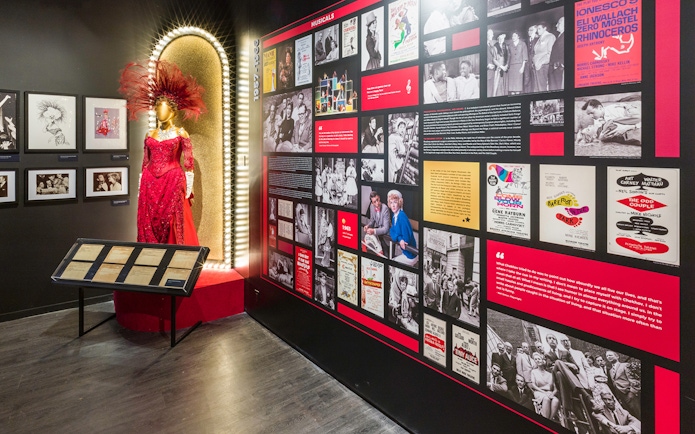 Exhibit at The Museum of Broadway featuring a red costume and historical Broadway posters.