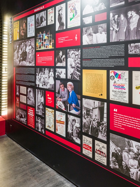 Exhibit at The Museum of Broadway featuring a red costume and historical Broadway posters.