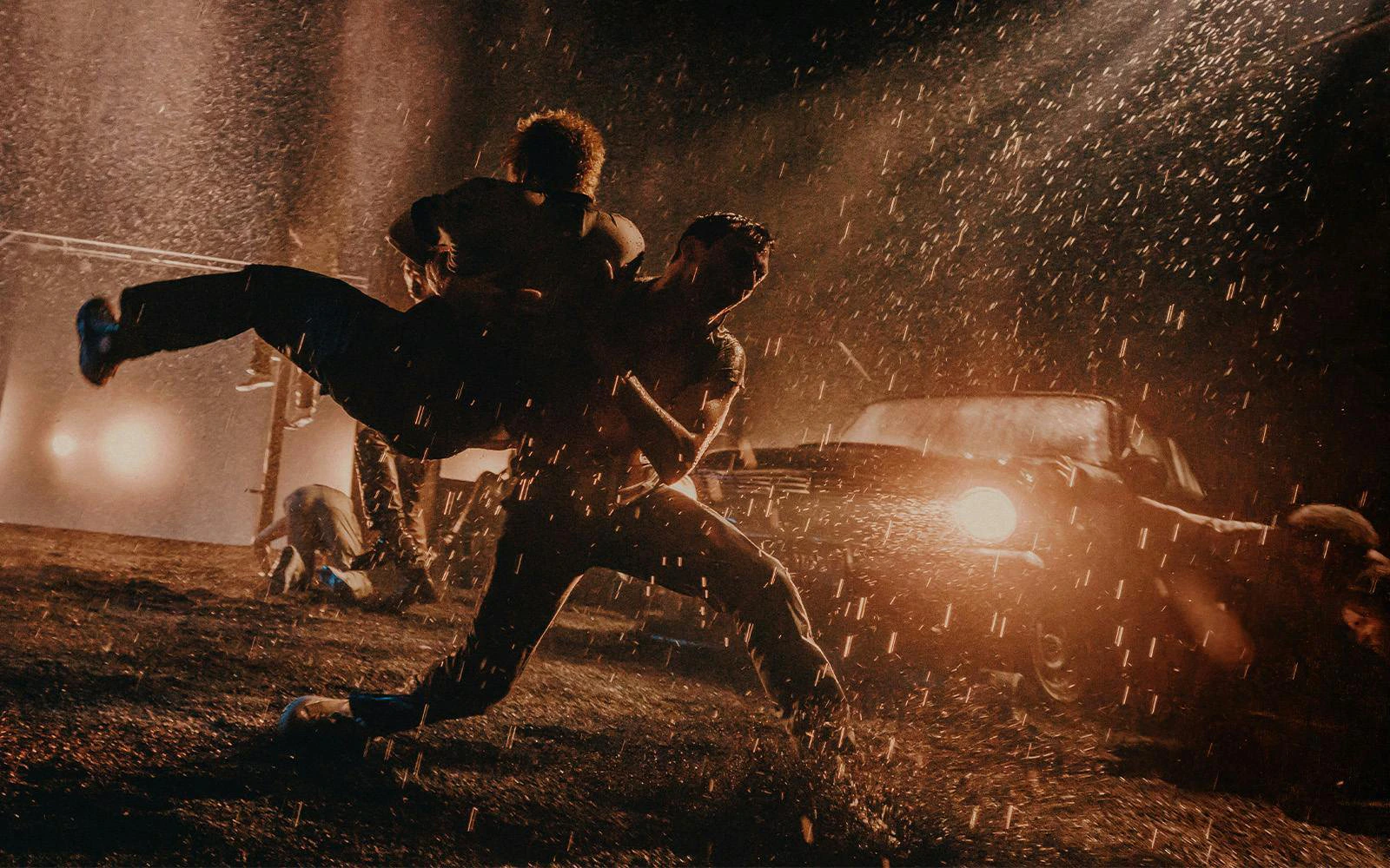 Actors performing a dramatic rain-soaked fight scene in The Outsiders on Broadway.