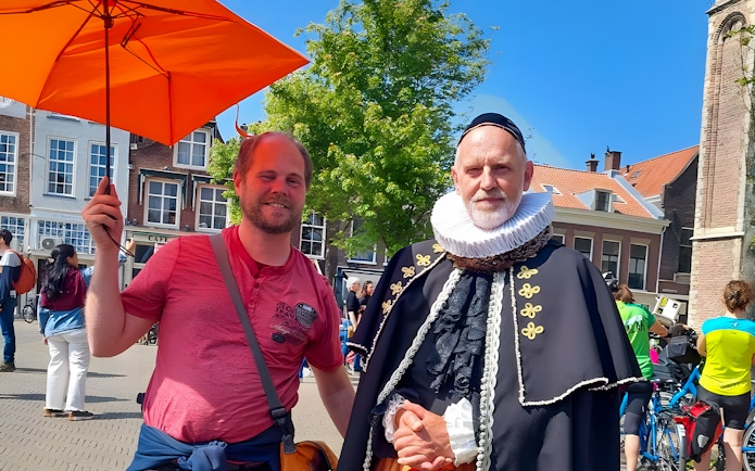 Tour guide with orange umbrella and man in historical costume in Delft.