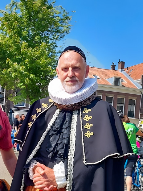 Tour guide with orange umbrella and man in historical costume in Delft.