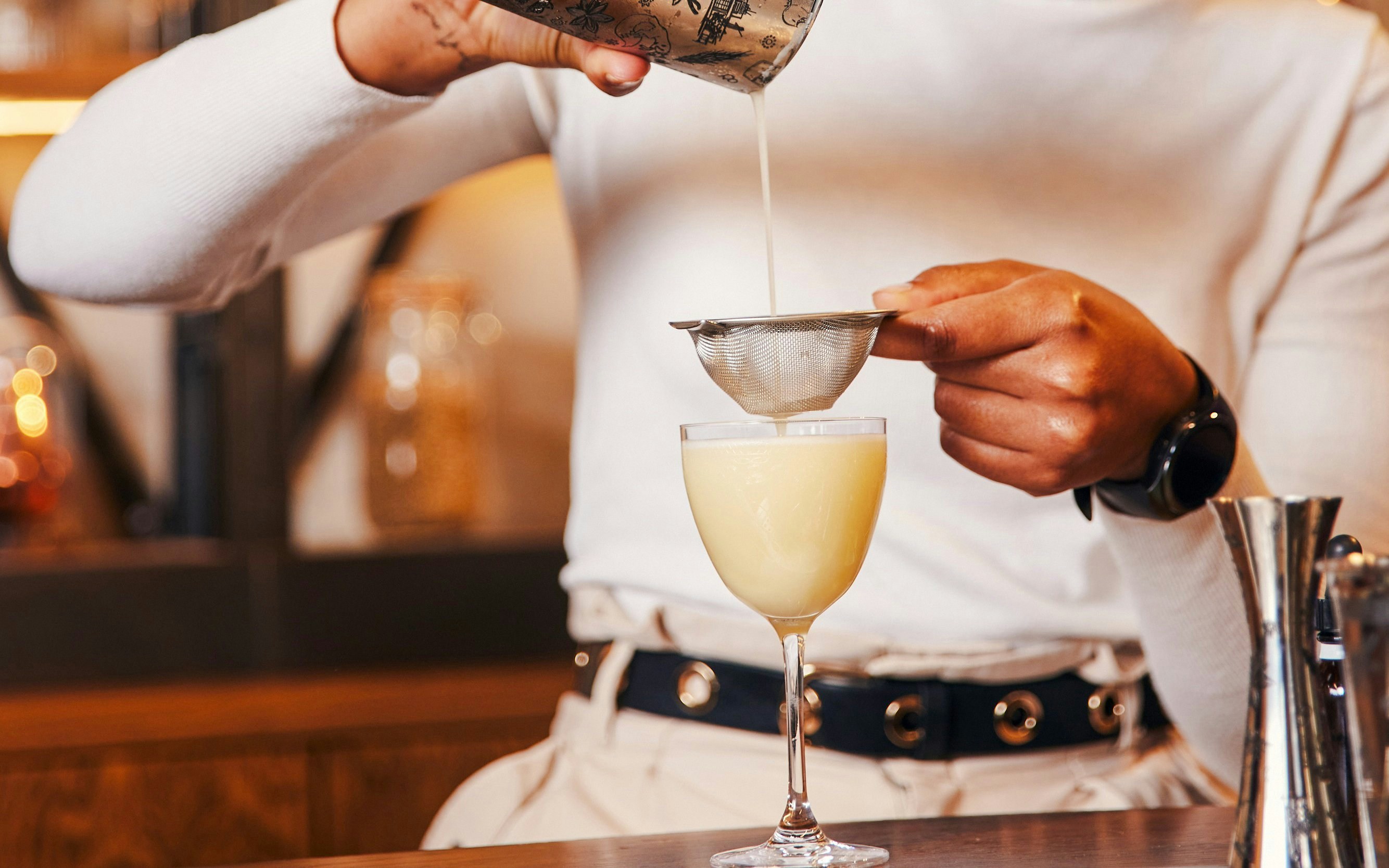 Pouring cocktail through strainer at Roe & Co Distillery.