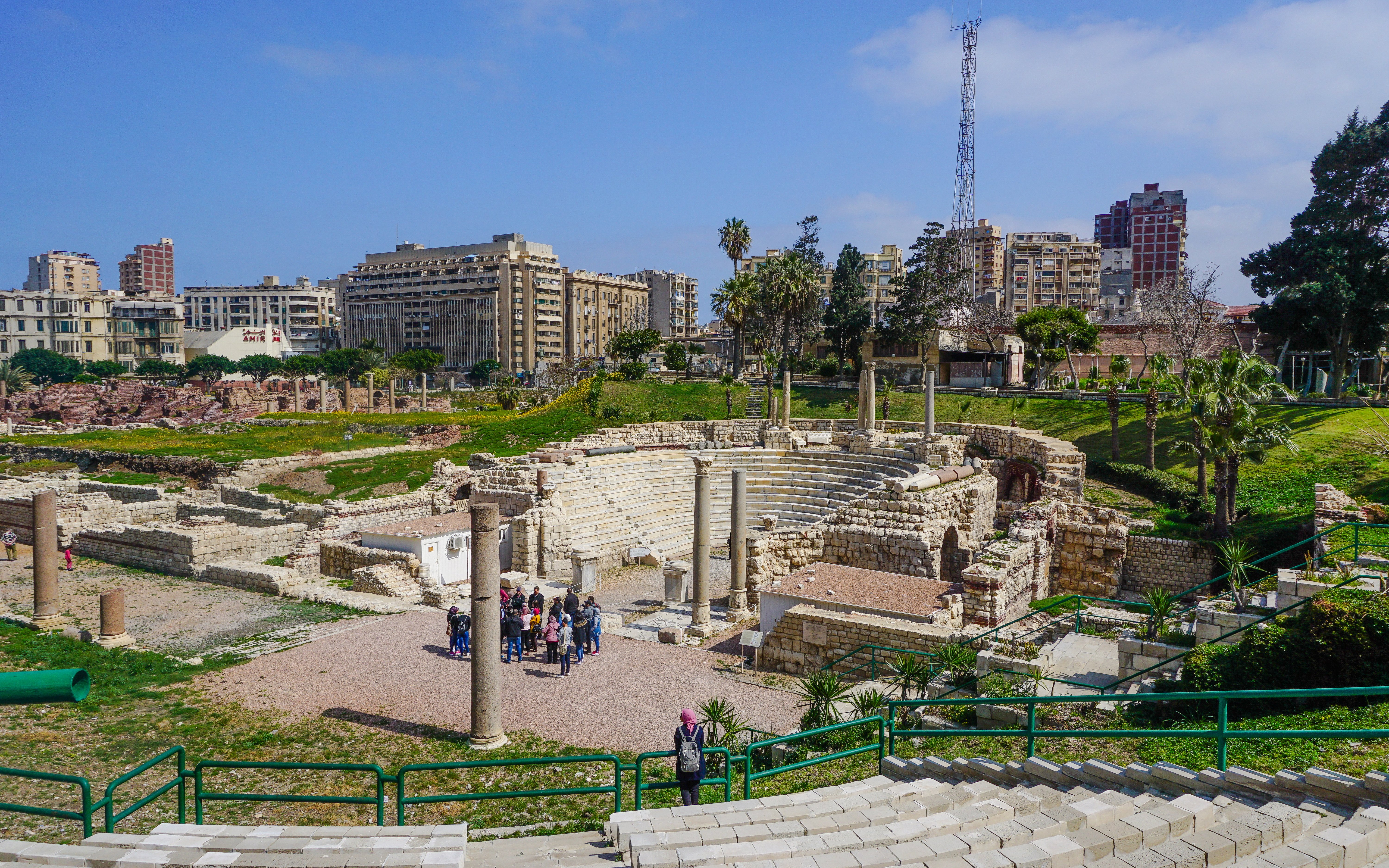 Ancient Roman Theatre ruins in Kom El-Deka, Alexandria, with cityscape in the background.