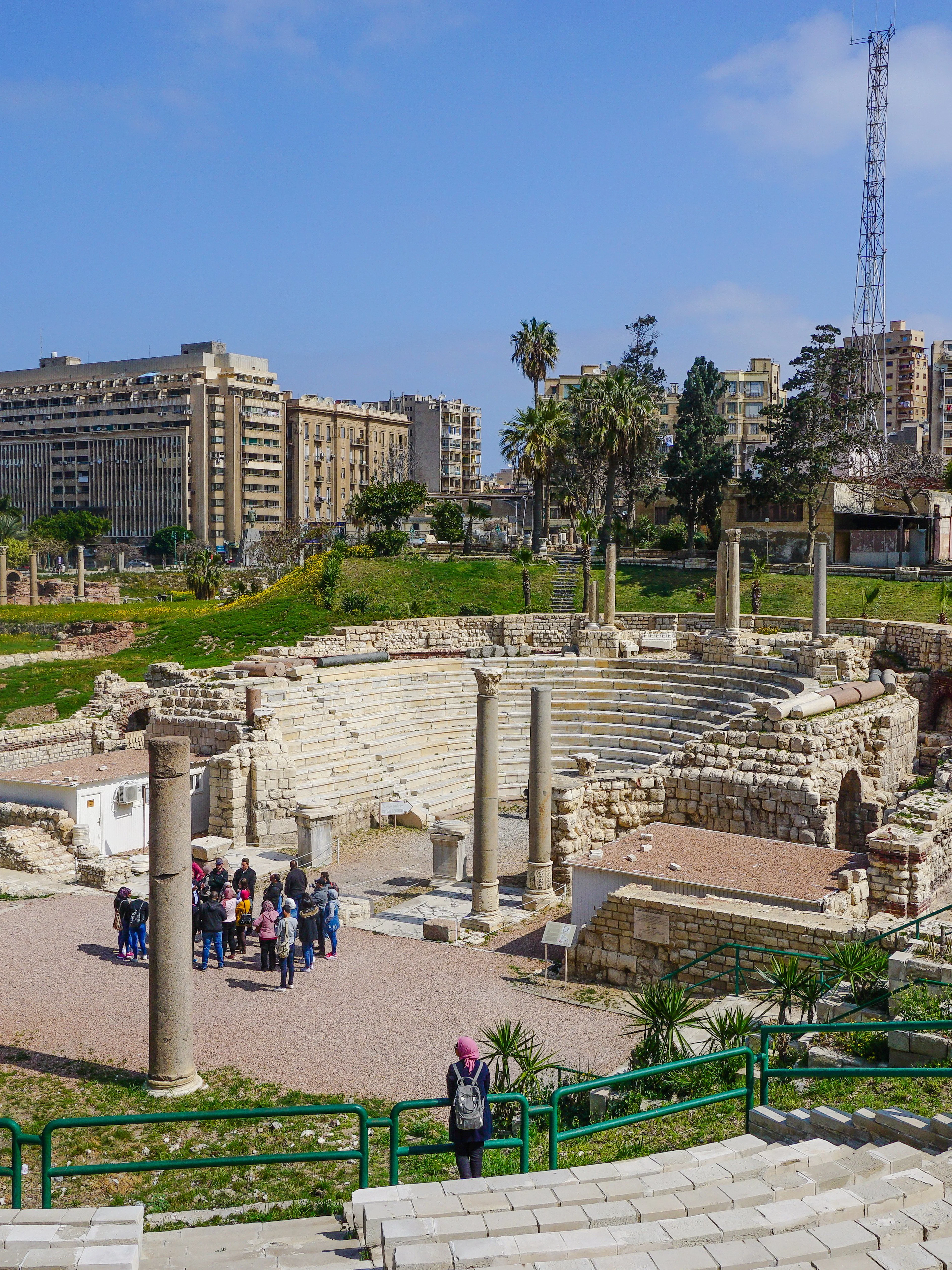 Ancient Roman Theatre ruins in Kom El-Deka, Alexandria, with cityscape in the background.