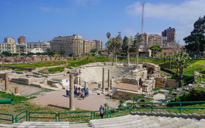 Ancient Roman Theatre ruins in Kom El-Deka, Alexandria, with cityscape in the background.