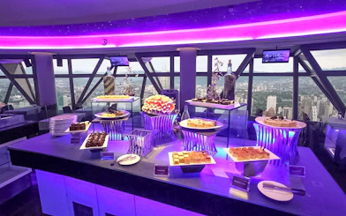 Buffet spread at Atmosphere 360 Revolving Restaurant with city view in background.