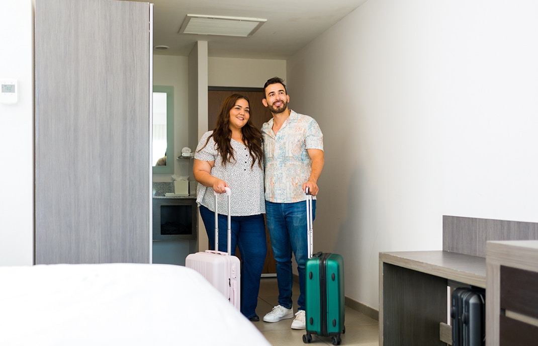 Young couple is entering their hotel room with their luggage