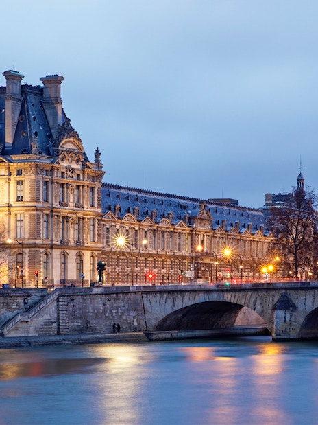 Louvre Museum and Seine River illuminated at night, Paris sightseeing cruise.