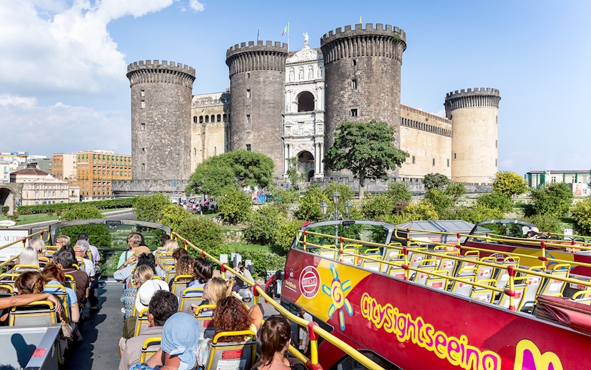 City sightseeing bus near Castel Nuovo, Naples, with tourists on board.