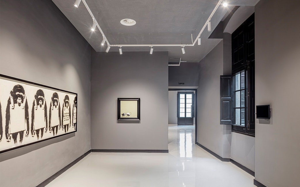 Exhibit of modern art at Moco Museum in Barcelona, featuring framed artworks on a gray wall.