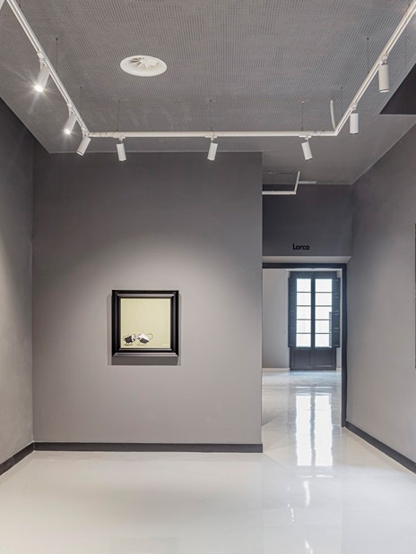 Exhibit of modern art at Moco Museum in Barcelona, featuring framed artworks on a gray wall.