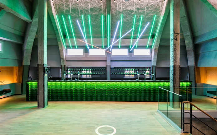 Heineken rooftop bar with green neon lights and bottle display in Amsterdam.
