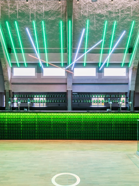 Heineken rooftop bar with green neon lights and bottle display in Amsterdam.
