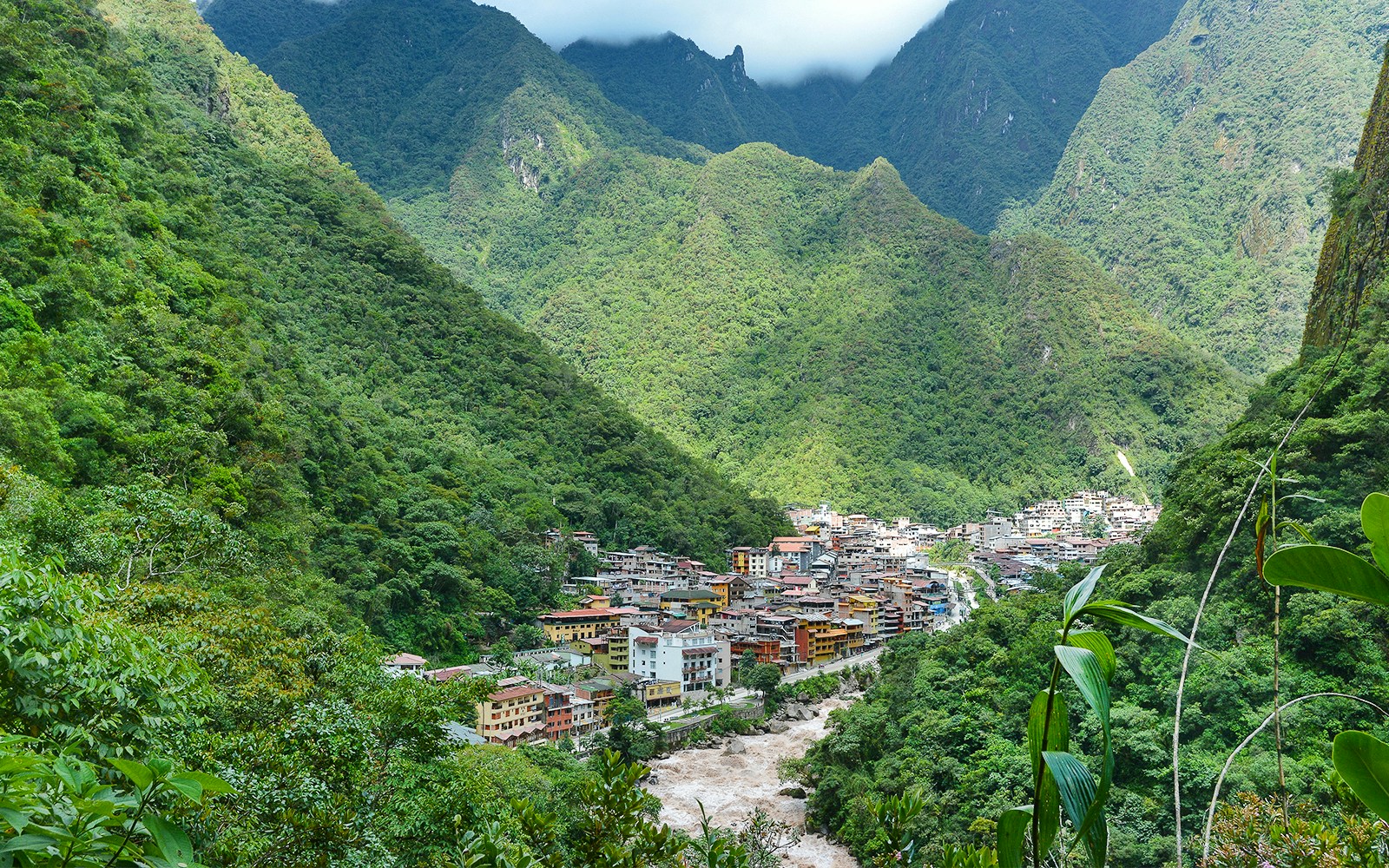 Aerial view of Aguas Calientes, Peru nestled in lush green mountains.