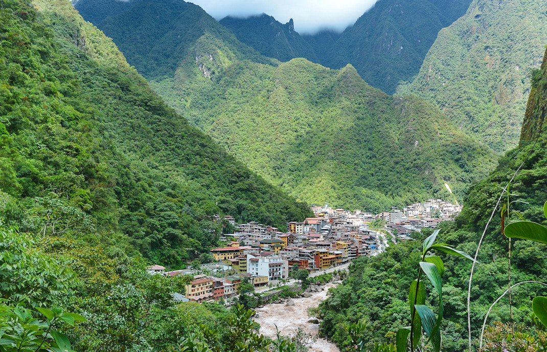 Aerial view of Aguas Calientes, Peru nestled in lush green mountains.