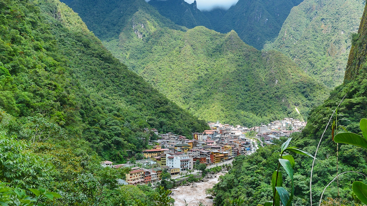 Aerial view of Aguas Calientes, Peru nestled in lush green mountains.
