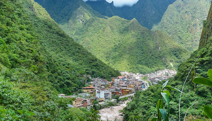 Aerial view of Aguas Calientes, Peru nestled in lush green mountains.