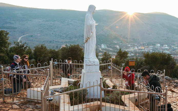 Pilgrims praying at Virgin Mary statue on Apparition Hill, Medjugorje, Bosnia and Herzegovina.