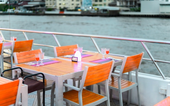 Riverside dining setup on a cruise with drinks and table settings.