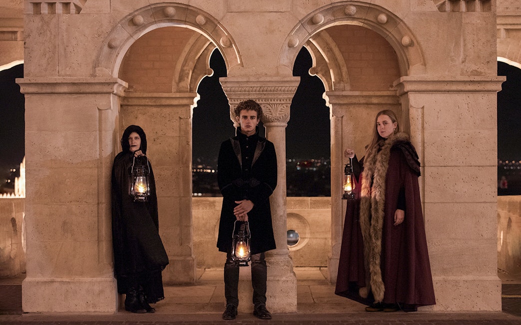 People in period costumes holding lanterns at Buda Castle during evening tour in Budapest.