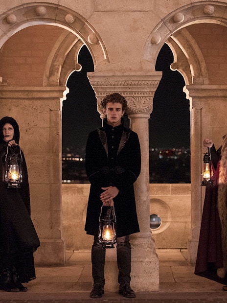 People in period costumes holding lanterns at Buda Castle during evening tour in Budapest.