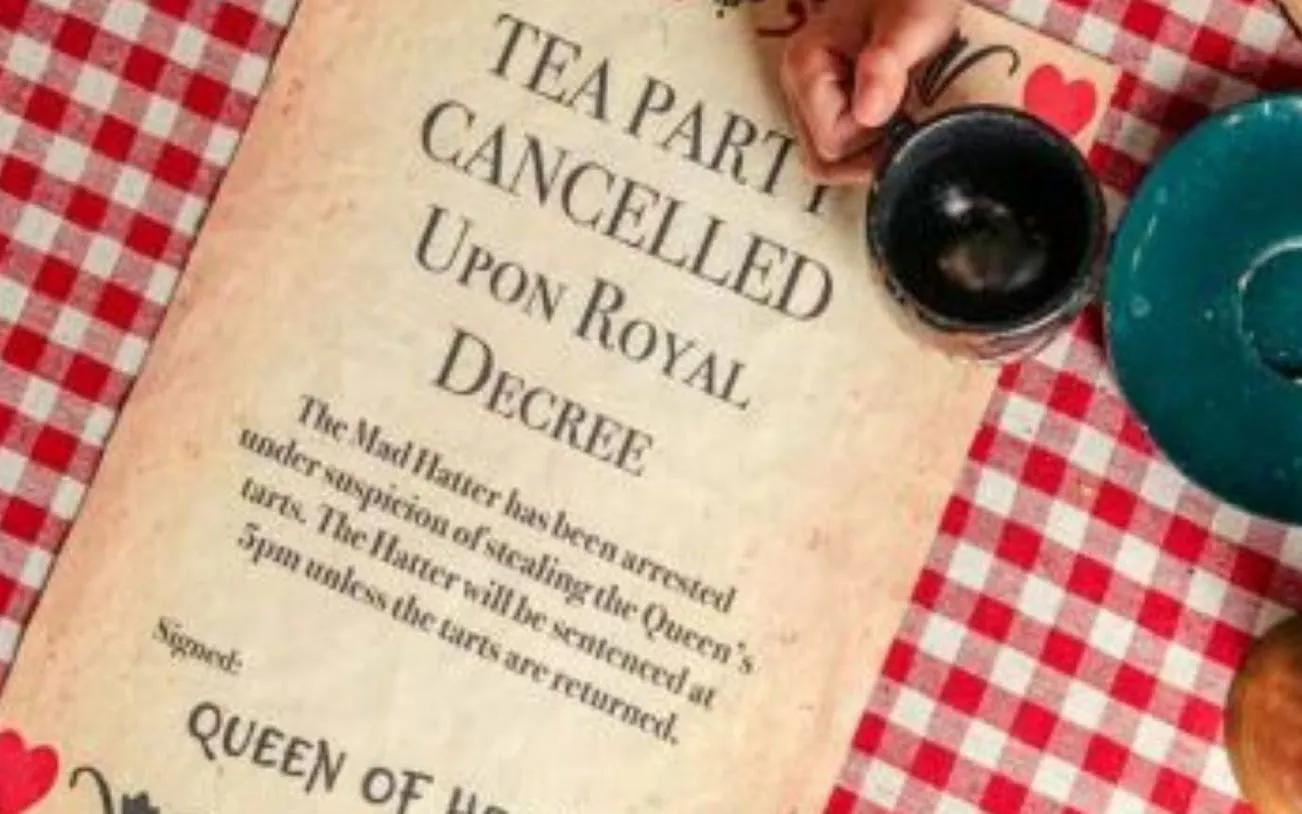 Tea party cancellation notice on checkered tablecloth at Alice in Puzzleland Dubai escape room.