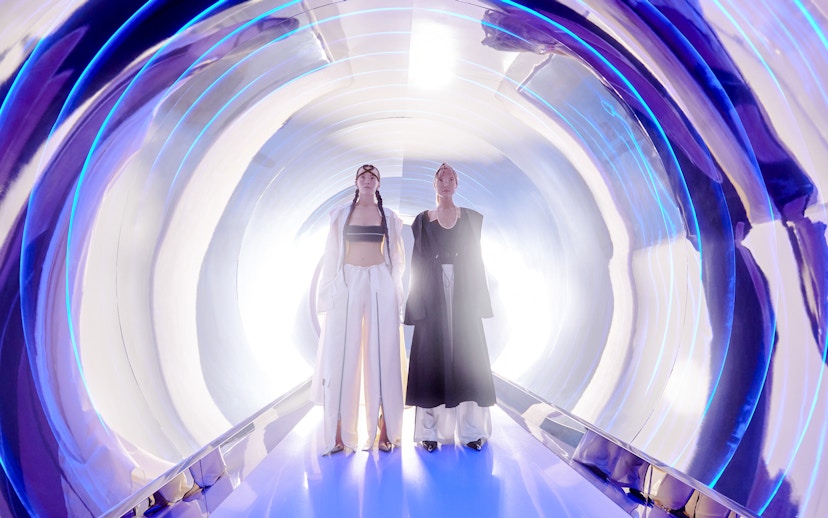 Women in high fashion at AYA Universe, Dubai, standing in a futuristic tunnel.