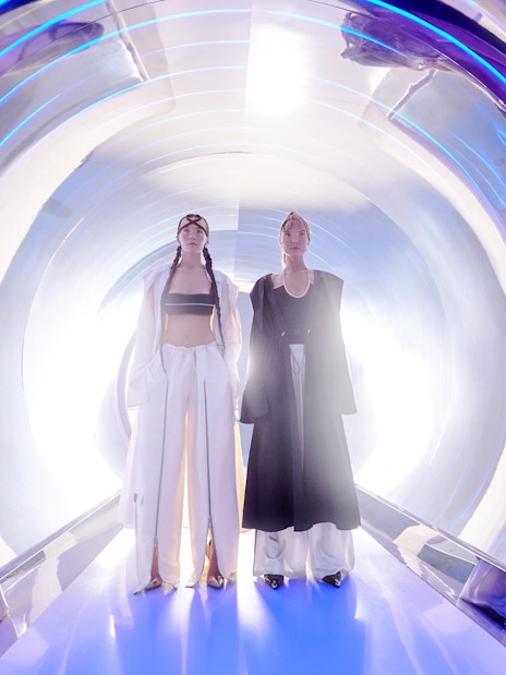 Women in high fashion at AYA Universe, Dubai, standing in a futuristic tunnel.
