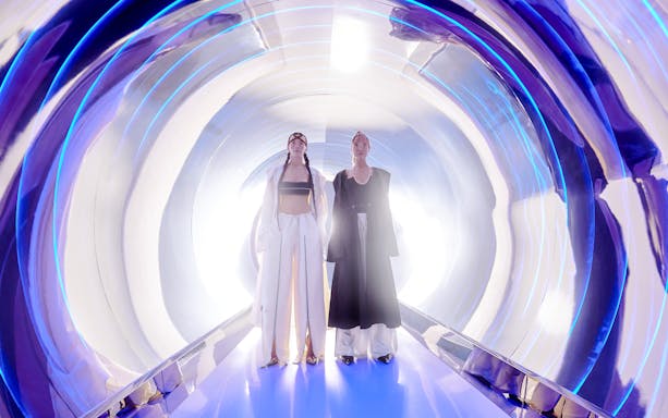 Women in high fashion at AYA Universe, Dubai, standing in a futuristic tunnel.