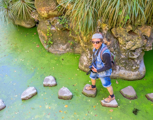 Tour guide with group exploring Quinta da Regaleira gardens, Sintra, Portugal.