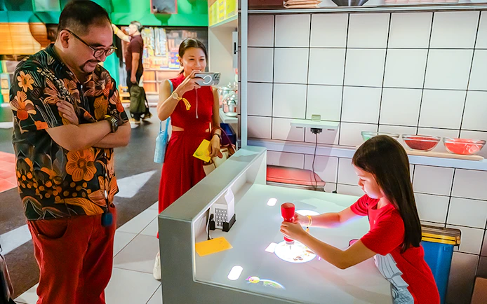 Family explores digital kitchen exhibit with interactive food projections.