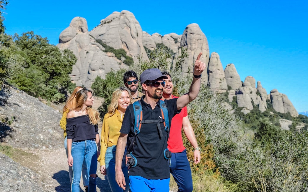 Tourists hiking with guide towards Montserrat Monastery in Spain.