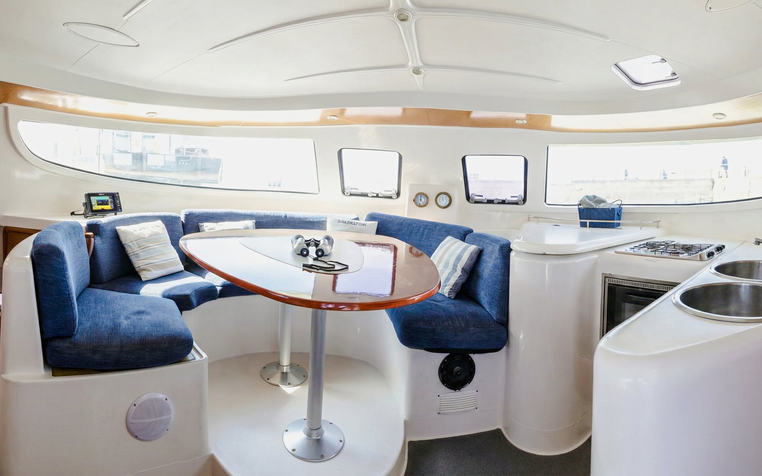Interior of a catamaran with seating and kitchen area, La Maddalena Archipelago tour.