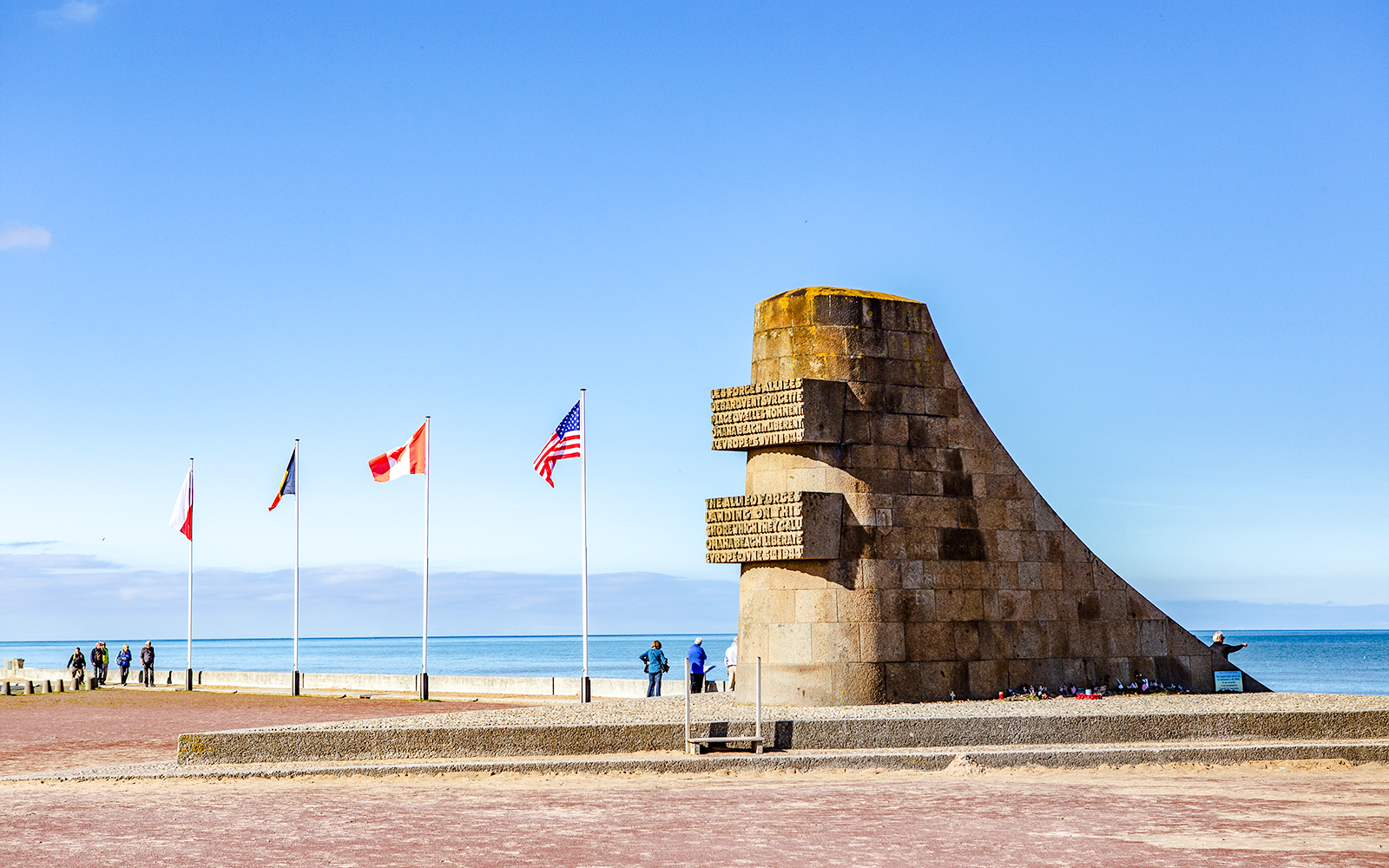Monument and flags at Omaha Beach, Normandy, France, with ocean view.