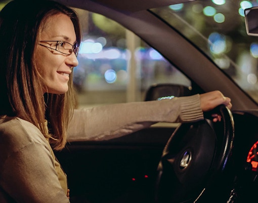 Woman driving car by night in the city