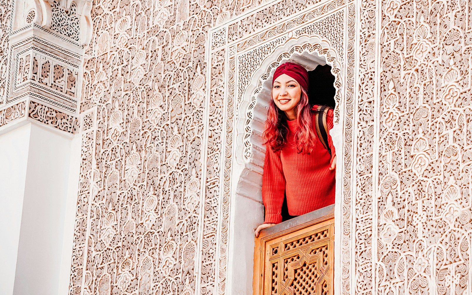Woman looking out from ornate window at Ben Youssef Madrasa, Marrakech, Morocco.