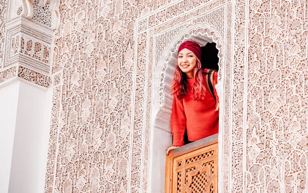 Woman looking out from ornate window at Ben Youssef Madrasa, Marrakech, Morocco.