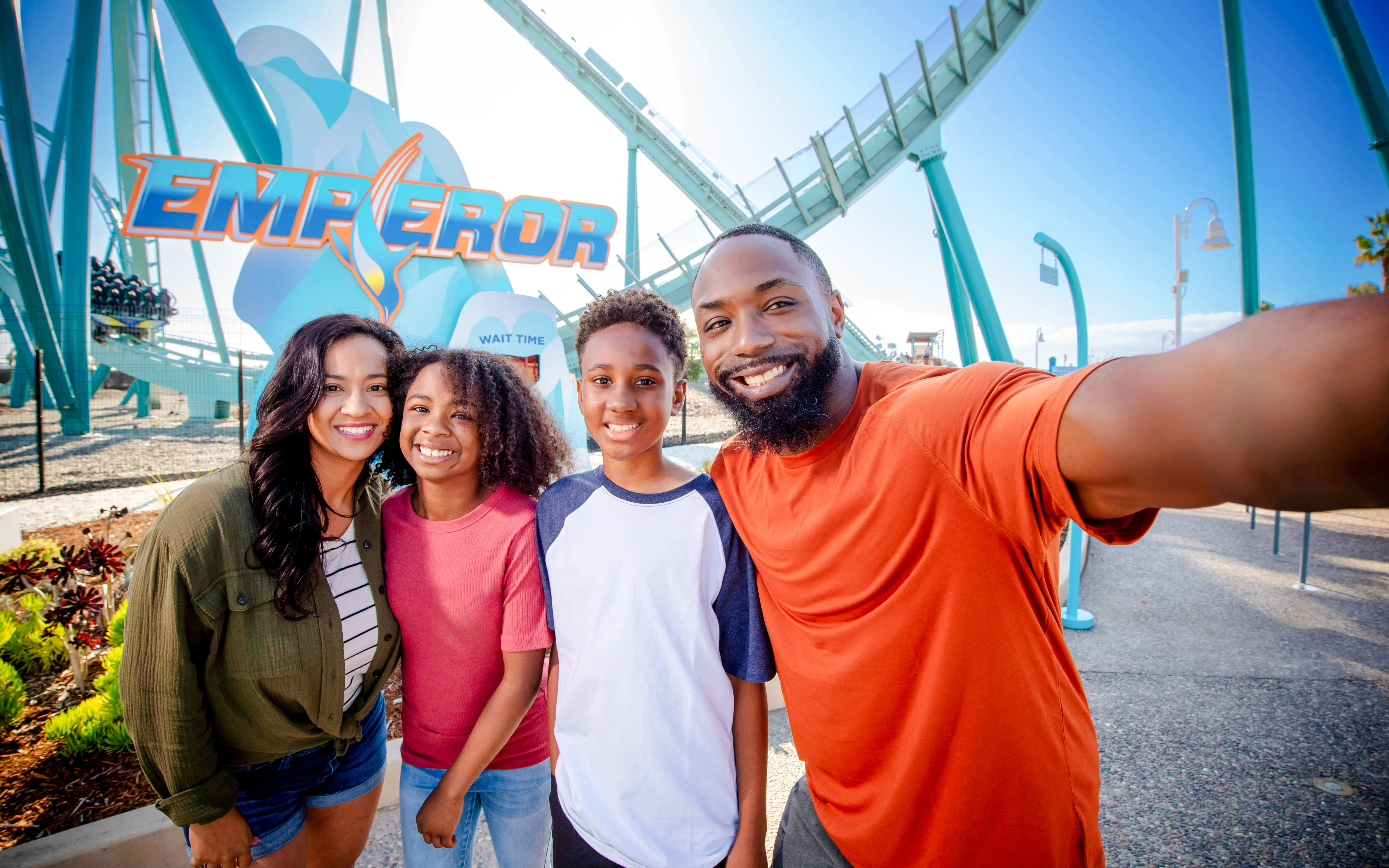 Family posing in front of the Emperor roller coaster at SeaWorld San Diego.