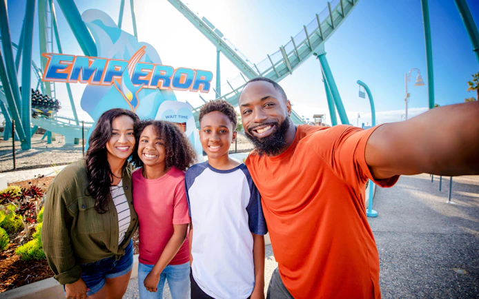 Family posing in front of the Emperor roller coaster at SeaWorld San Diego.