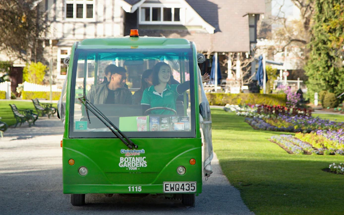 Tour tram in Christchurch Botanic Gardens with guide and visitors.