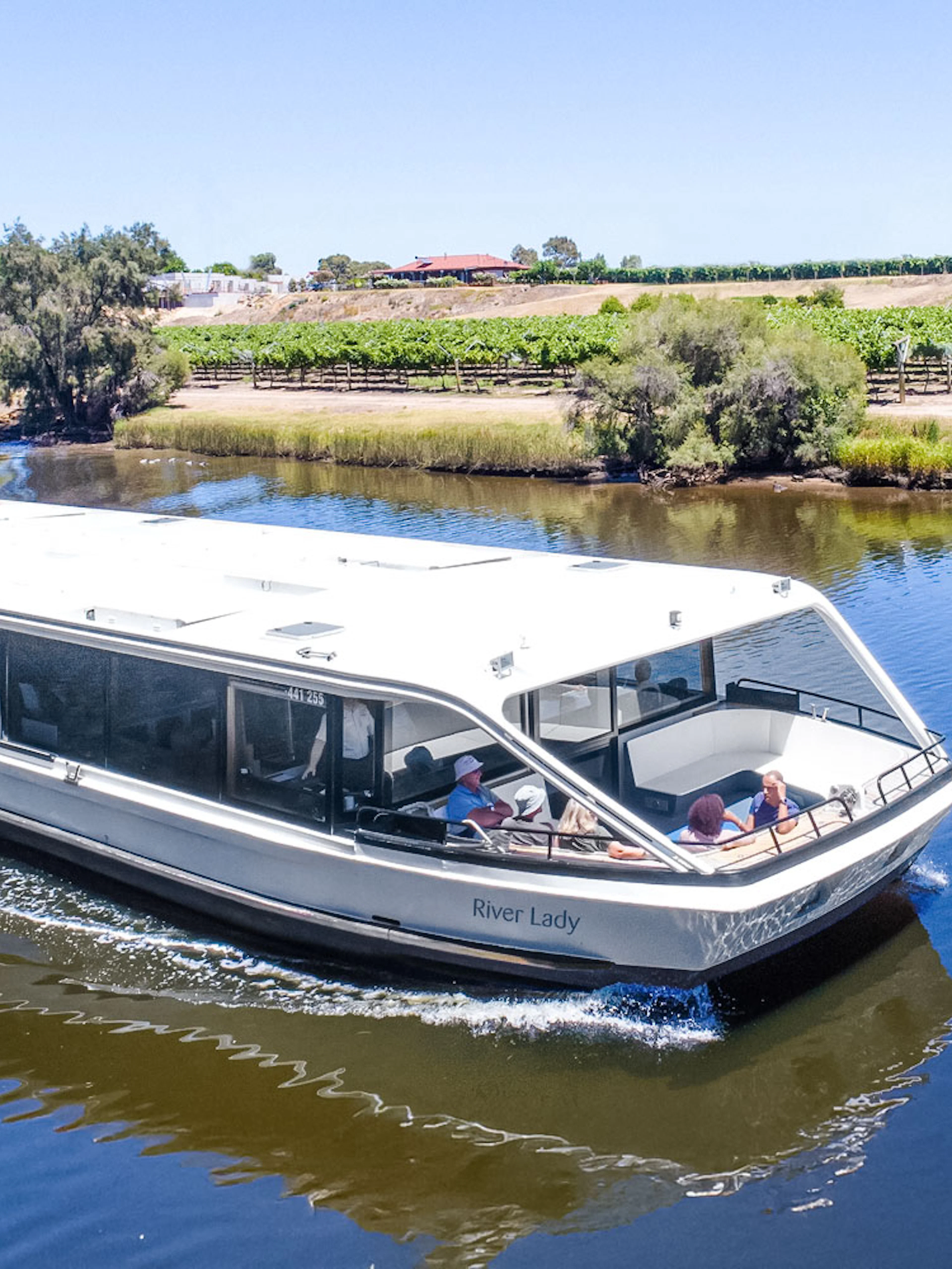Cruise boat on Swan River with vineyards in Swan Valley, Australia.