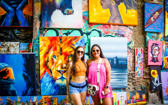 Tourists in front of colorful street art in Cartagena's Walled Old City, featuring vibrant paintings.
