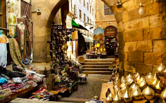 Khan el-Khalili market alley with shops displaying textiles and brassware, Cairo.
