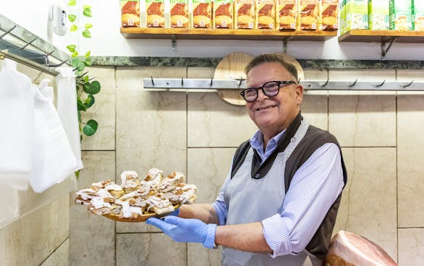 Man in Trastevere shop holding a platter of porchetta slices, Rome.